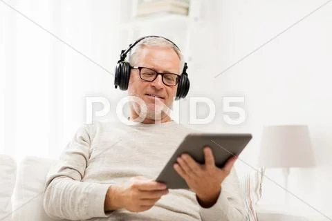 Senior man with tablet pc and headphones at home Stock Photos