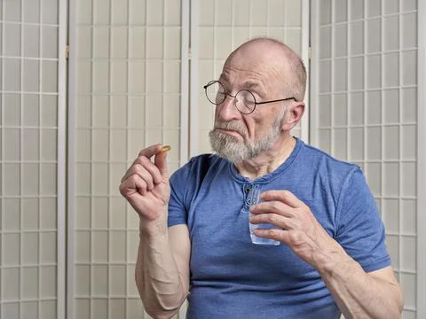 Senior man is taking a medicine or supplement pill Stock Photos