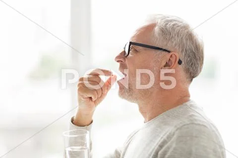 Senior man taking medicine pill at home Stock Photos