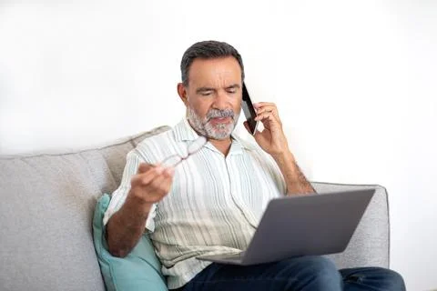 Senior Man Talking on Phone Solving Problems With Laptop Indoors 스톡 사진