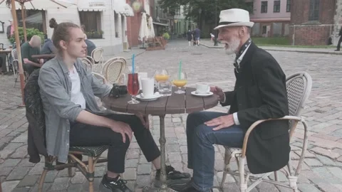 Senior man talks to happy guy sitting at table with drinks Stock Footage 139796290