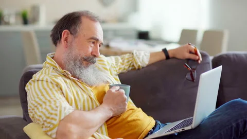 Senior man with tea thinking on project at home Stock Footage 153873451