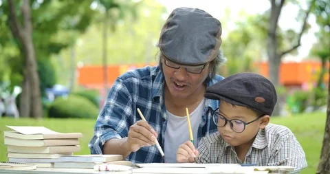 Senior man teaching child how to paint in the park. Video stock 99323215