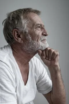 Senior man thinking or try to remember alone on bed in white room Stock Photos