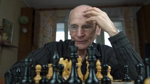Senior man thinks moving white knight chess figure closeup Stock Footage 126766860