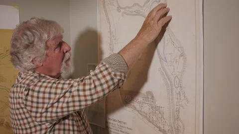 Senior man traces route on a map mounted on wall, 4k Stock Footage 171349741