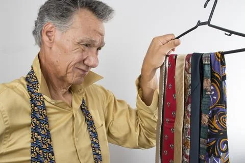 Senior Man trying to select a necktie to wear Stock Photos