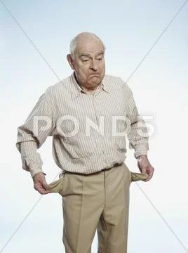 Senior man turns his pockets inside out to symbolize having no money Stock Photos