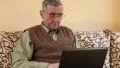 Senior man types text using laptop. Man on a sofa with notebook HD Footage