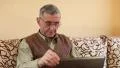 Senior man types text using laptop. Man on divan with notebook HD Footage