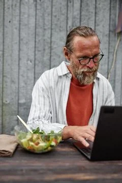 Senior Man Using Computer at Table Working Outdoors Foto stock
