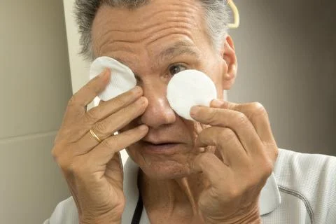 Senior man using cotton pads for eye relief Stock Photos