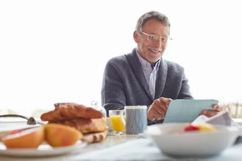 Senior man using digital tablet at patio breakfast Stock Photos