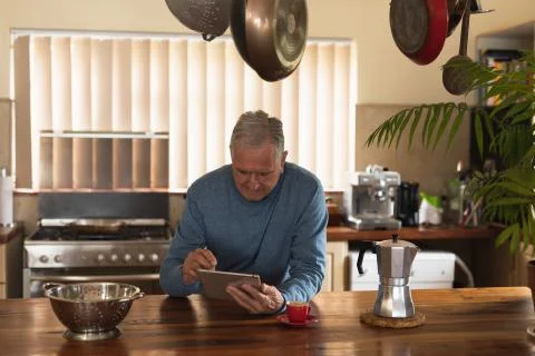 Senior man using digital tablet on his kitchen 写真素材