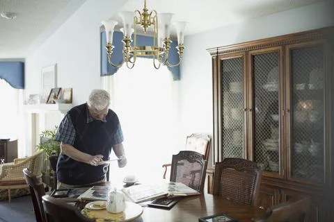 Senior man using digital tablet at dining table with photograph albums Stock Photos