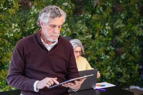 Senior man using digital tablet in modern workspace Stock Photos