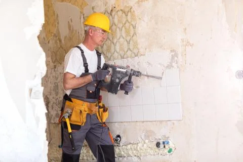 Senior man using drill in the reconstruction of the building Stock Photos