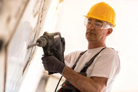 Senior man using drill in the reconstruction of the building Stock Photos