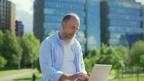 Senior man using laptop on bench outside Stock Footage 135462656
