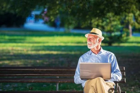 Senior man using laptop computer at rest in the park outdoors Stock Photos