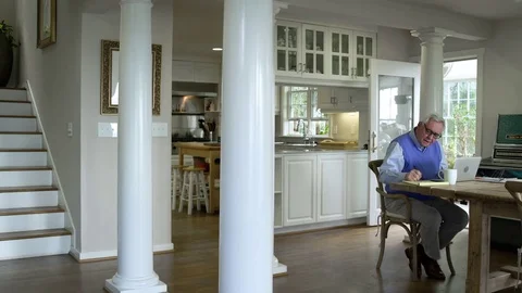 Senior man using a laptop in a dining room 動画素材 83394585