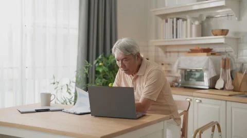 Senior man using laptop home office kitchen table for remote work, online m.. Stock Footage 332748698