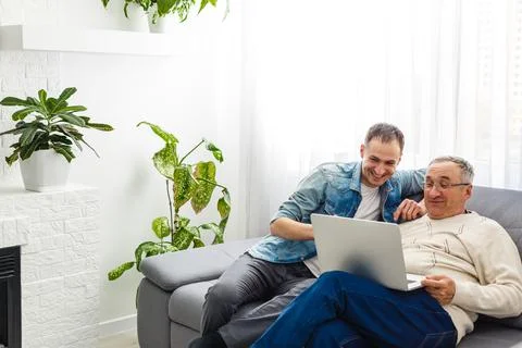 Senior man using laptop PC with his adult son Stock Photos