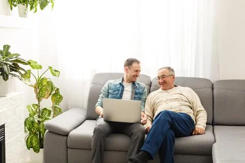 Senior man using laptop PC with his adult son Stock Photos