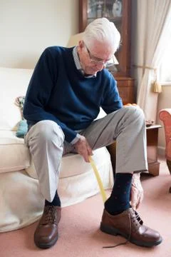 Senior Man Using Long Handled Shoe Horn To Put On Shoes Foto stock