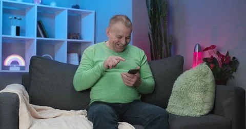 Senior Man Using Mobile App Sit on Sofa, Senior Man Texting Typing Message Hold Stock Footage 194474873