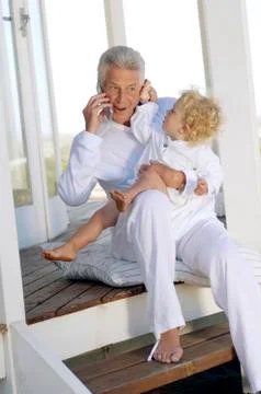 Senior man using mobile phone, with little boy Stock Photos