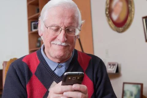 Senior man using mobile phone at home Stock Photos