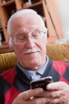 Senior man using mobile phone at home Stock Photos