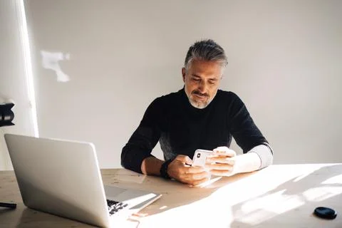 Senior man using mobile phone on table near laptop Foto stock