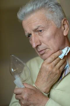 Senior man using a nebulizer makes inhalation Stock Photos