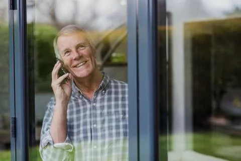 Senior Man Using Phone At Window Photos