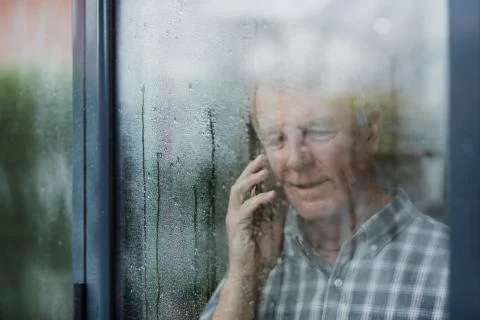 Senior Man Using Phone At Window Fotos Stock