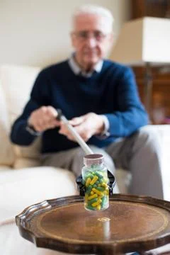 Senior Man Using Reaching Arm To Pick Up Medication At Home Stock Photos