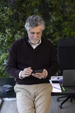 Senior man using smartphone in modern office Stock Photos