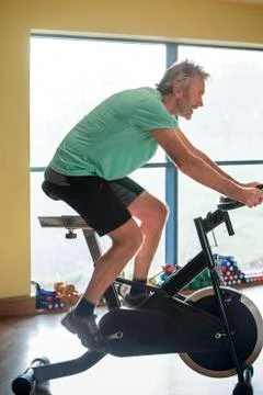 Senior man using a spinning bike Stock Photos