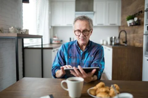 Senior man using tablet at kitchen table Stock Photos
