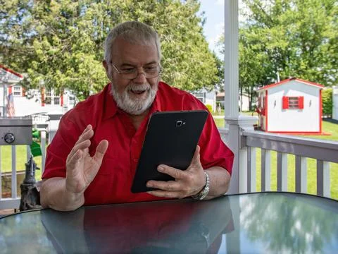 Senior Man Using Tablet Outside on a Sunny Day in a Park Setting With Build.. Stock Photos