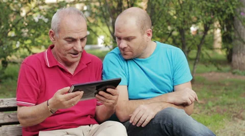 Senior man using tablet PC with his adult son on park 動画素材 32356572