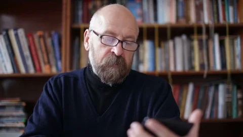 Senior man using tablet sitting on white couch in living room. Starting and Stock Footage 74734964
