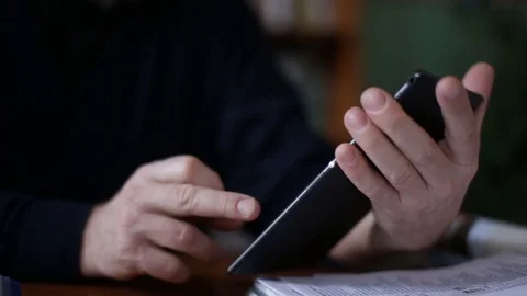 Senior man using tablet sitting on white couch in living room. Starting and Stock Footage 74736704