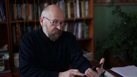 Senior man using tablet sitting on white couch in living room. Starting and Stock Footage 74738328