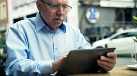 Senior man using tablet while sitting in cafe in city Stock Footage 65445377