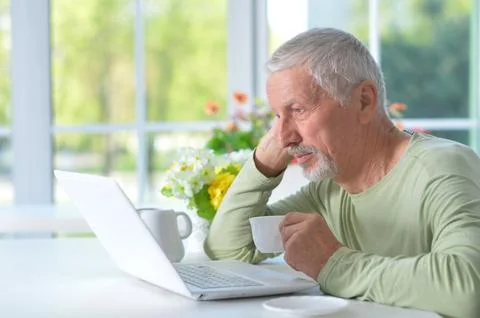Senior man using tablet while drinking tea Stock Photos