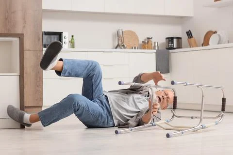 Senior man with walker falling on floor in kitchen Stock Photos