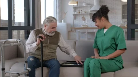 Senior man with walking cane playing backgammon with black female caregiver Stock Footage 303325988